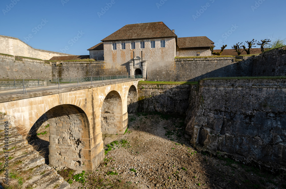 View of the old citadel in the city of Besancon, France. There is a bridge across a deep moat and entrance gate. Scenery. Background. View of the old citadel in the city of Besancon, France. There is a bridge across a deep moat and entrance gate. Scenery. Background.
