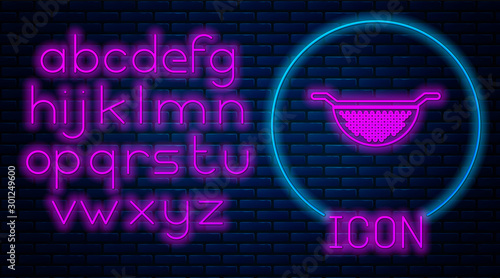 Glowing neon Kitchen colander icon isolated on brick wall background. Cooking utensil. Cutlery sign. Neon light alphabet. Vector Illustration