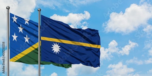 Solomon Islands and Nauru flag waving in the wind against white cloudy blue sky together. Diplomacy concept, international relations.