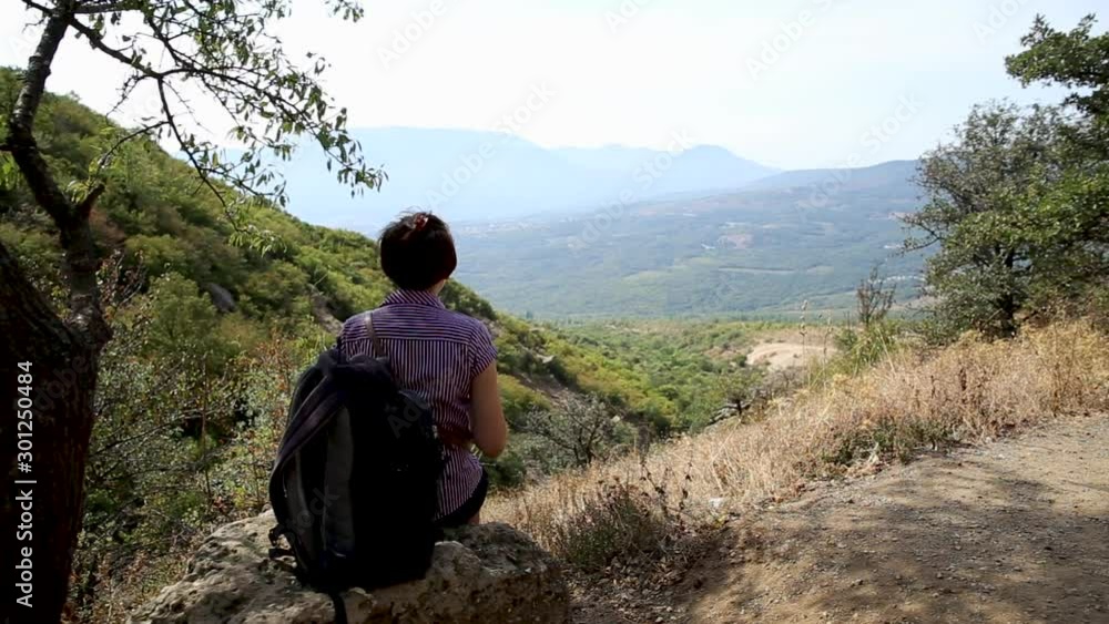 Young woman is sitting on stone in Ghost Valley. Beautiful summer landscape. Demerdgi mountains, Crimea. Young woman is sitting on stone in Ghost Valley. Beautiful summer landscape. Demerdgi mountains, Crimea.