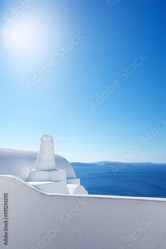 Bright sun flooding a classic Greek island scene of whitewashed walls and blue Mediterranean view of Santorini caldera