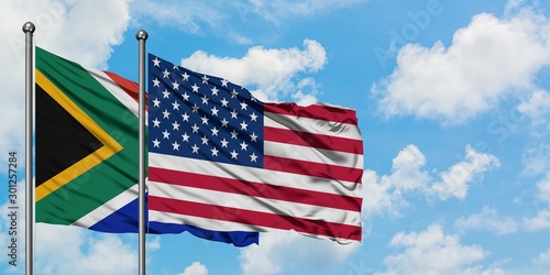 South Africa and United States flag waving in the wind against white cloudy blue sky together. Diplomacy concept, international relations.