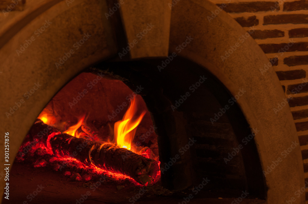 Classic stone pizza oven with fire burning inside.