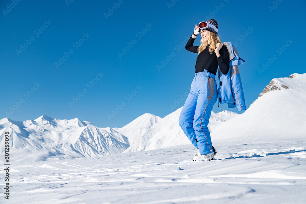 Female skier standing on beautiful mountain landscape background. Winter, ski, snow, vacation, sport, leisure, lifestyle concept
