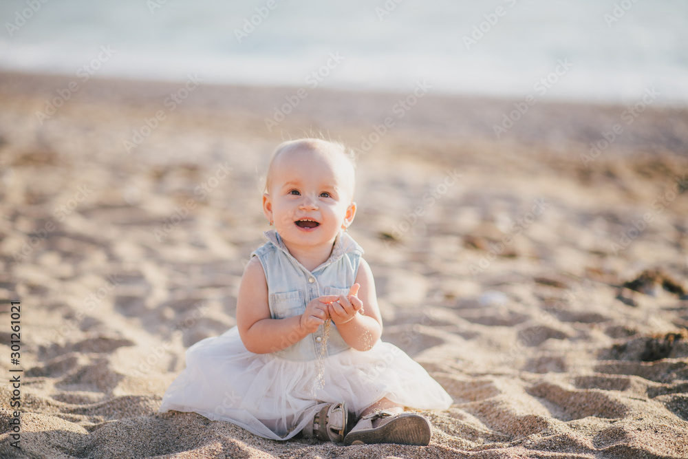 Happy baby girl sitting on sand near sea at beach. Happy baby girl sitting on sand near sea at beach.