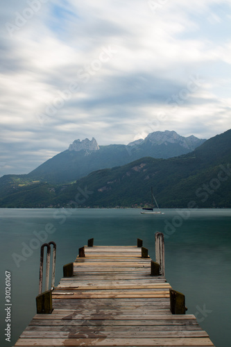 long exposure of a pier at lake annecy with dramatic clouds in the sky