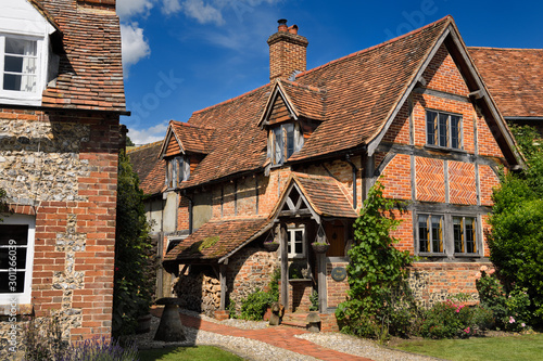 Fototapeta Red brick and roof tile English Tudor cottages in Turville in full sun with blue