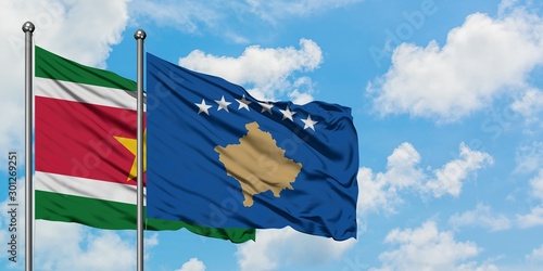 Suriname and Kosovo flag waving in the wind against white cloudy blue sky together. Diplomacy concept, international relations.