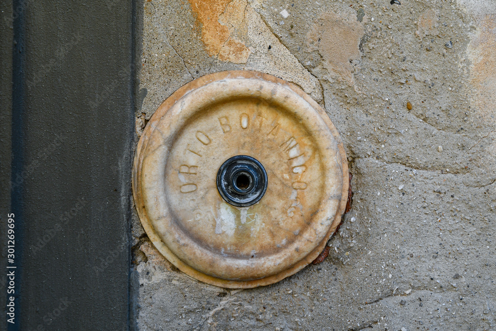 Close-up of the old marble doorbell of the Orto Botanico (