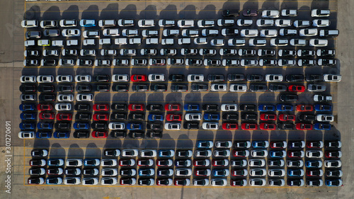 Aerial drone top down photo of new cars lined up in automobile port terminal for import and export