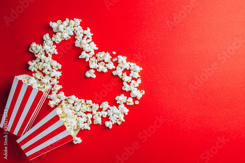 Tasty salted popcorn in striped cardboard box on red background. Top view. Fl...
