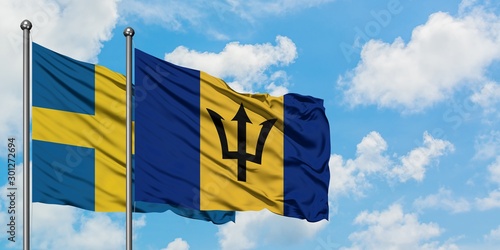 Sweden and Barbados flag waving in the wind against white cloudy blue sky together. Diplomacy concept, international relations.