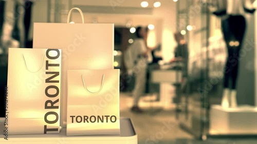 Paper shopping bags with TORONTO text against blurred store. Canadian shopping related clip photo
