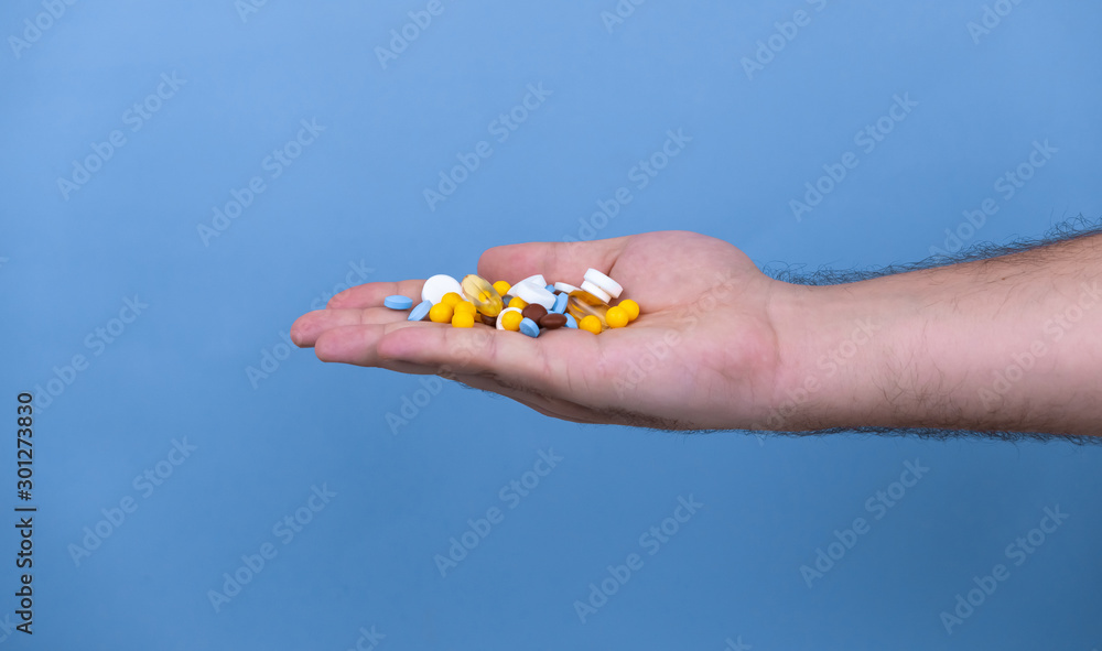 A pile of multi-colored pills in a male hand. A man holds pills in his hand. The concept of medicine, illness, health A pile of multi-colored pills in a male hand. A man holds pills in his hand. The concept of medicine, illness, health
