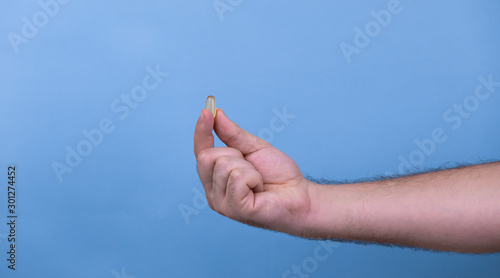 One pill in a male hand. A man holds pills in his hand. The concept of medicine, illness, health