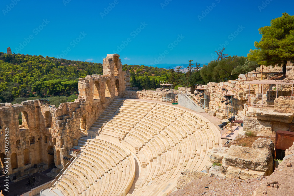 Panoramic image of ancient Greek theatre under Acropolis hill in Athens, Greece. Sunlit amphitheater on a sunny day with blue sky.