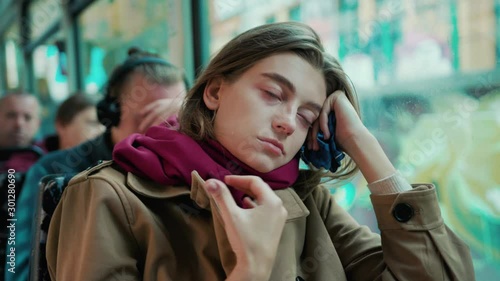 Young attractive woman coughs look on window on the tram on a cold autumn day at the start of the flu season disease fever flu grippe health illness infection influenza migraine sickness slow motion