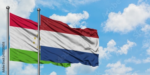 Tajikistan and Netherlands flag waving in the wind against white cloudy blue sky together. Diplomacy concept, international relations.