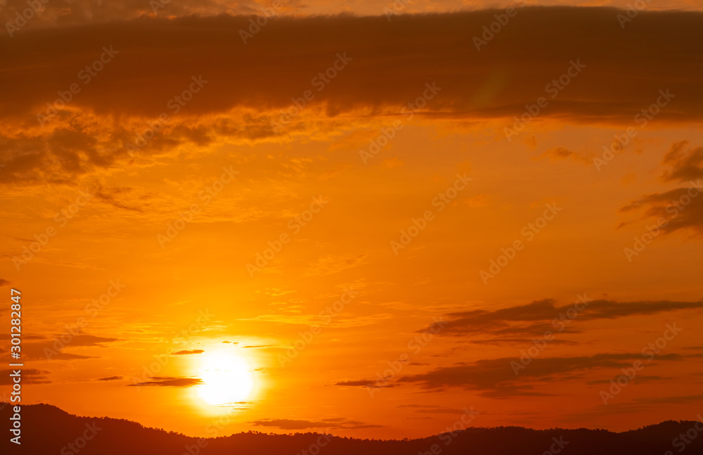 Beautiful orange sunset sky and clouds over the forest. Twilight sky. Nature background. Majestic view. Peaceful and relaxation abstract background. Big golden sun in the evening. Cloudscape at dusk.