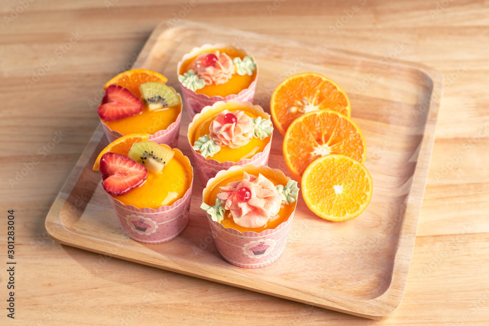 Orange cake in a wooden tray Decorated with orange, strawberry and kiwi Orange cake in a wooden tray Decorated with orange, strawberry and kiwi