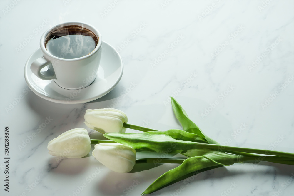 coffee background of a cup of hot black coffee with bunch of white tulip on white marble background coffee background of a cup of hot black coffee with bunch of white tulip on white marble background