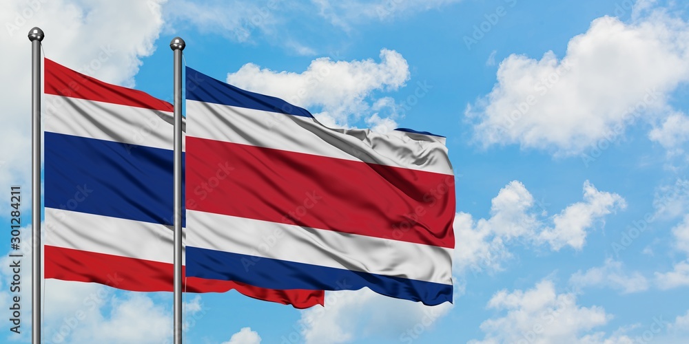 Thailand and Costa Rica flag waving in the wind against white cloudy blue sky together. Diplomacy concept, international relations.