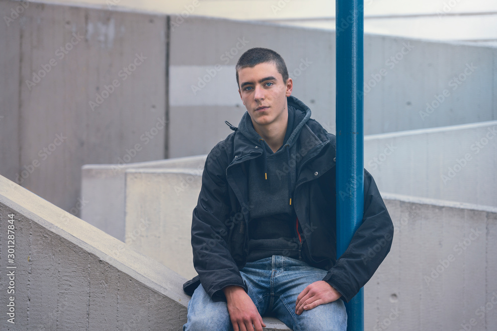 portrait of a casual young man in sitting on a concrete wall portrait of a casual young man in sitting on a concrete wall