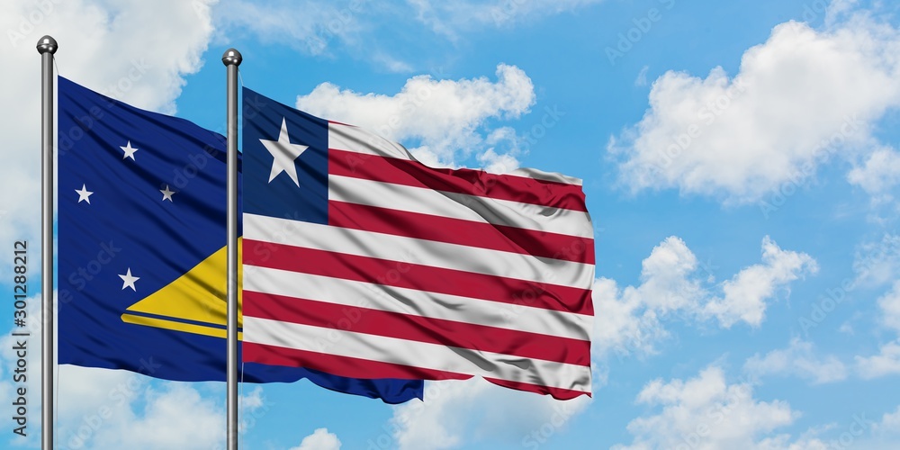 Tokelau and Liberia flag waving in the wind against white cloudy blue sky together. Diplomacy concept, international relations.