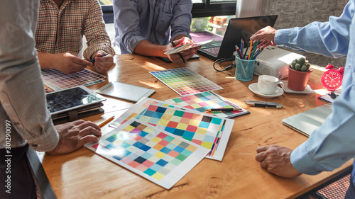 Group of Asian designers brainstorming working together with colleagues and color swatches in co-working workplace.