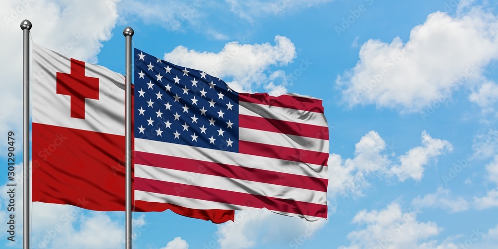 Tonga and United States flag waving in the wind against white cloudy blue sky together. Diplomacy concept, international relations. Tonga and United States flag waving in the wind against white cloudy blue sky together. Diplomacy concept, international relations.