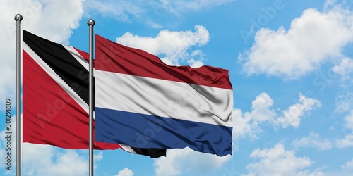 Trinidad And Tobago and Netherlands flag waving in the wind against white cloudy blue sky together. Diplomacy concept, international relations.