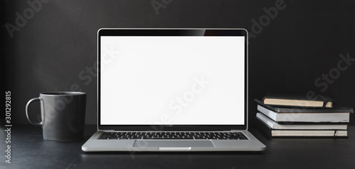 Cropped shot of modern office room with blank screen laptop computer and office supplies