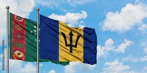 Turkmenistan and Barbados flag waving in the wind against white cloudy blue sky together. Diplomacy concept, international relations.