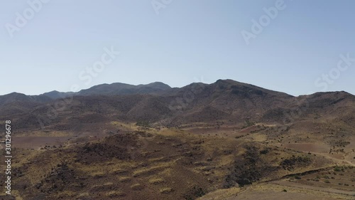 Aerial Drone shot of dry empty spanish desert with vegetation and mountains in Andalusia, Tabernas desert afternoon. Blue sky, Almeria, spain, western, far west, Sierra Nevada. Slow tracking in. 4K.
