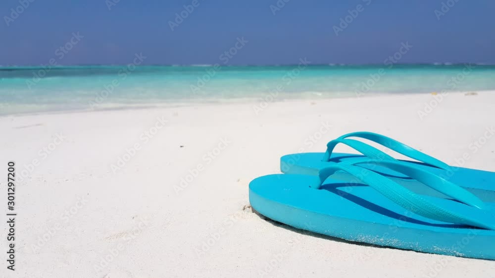 Summer Wear, Pair of the Blue Slippers At the Seashore With Perfect Calm Seas and Clear Blue Sky At the Background in Florida - Closed Shot Summer Wear, Pair of the Blue Slippers At the Seashore With Perfect Calm Seas and Clear Blue Sky At the Background in Florida - Closed Shot