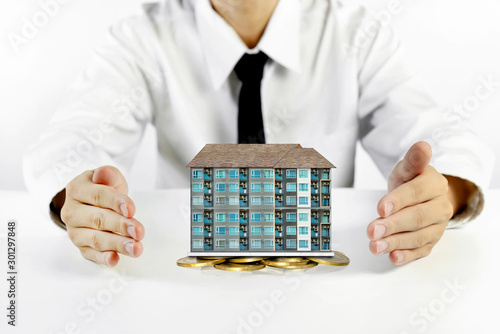 Fotografie businessman hands protecting condominium model with piles of golden coins