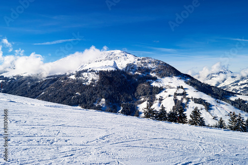 rugged ski slope on top of a frozen snowy mountain with the top of the alpine mountains in the background