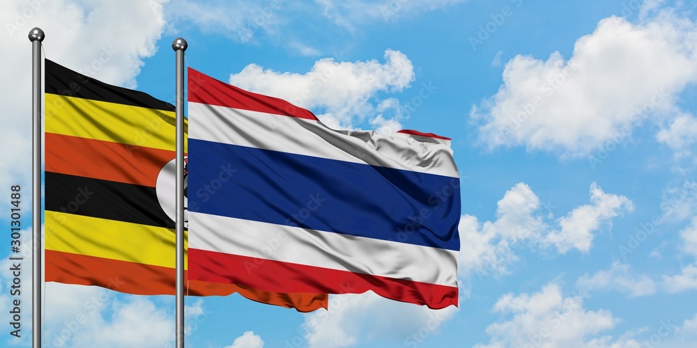 Uganda and Thailand flag waving in the wind against white cloudy blue sky together. Diplomacy concept, international relations.