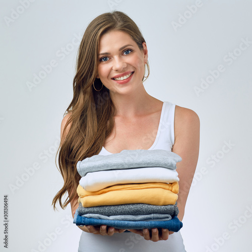 smiling young woman holding stack of foldet clothes photo