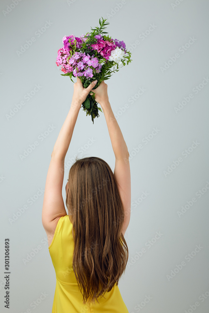 Woman standing back and holding flowers overhead. Woman standing back and holding flowers overhead.