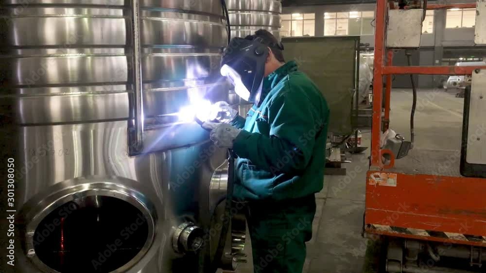 Worker welding stainless steel tank, using TIG, MIG welder, close up, dolly, slide, movement. The welder uses a mask to protect your eyes. Scene A. Worker welding stainless steel tank, using TIG, MIG welder, close up, dolly, slide, movement. The welder uses a mask to protect your eyes. Scene A.