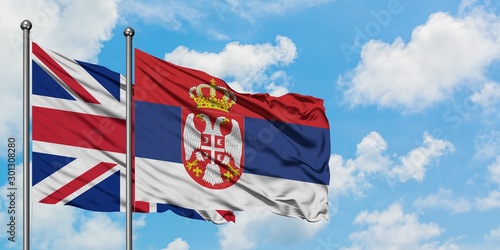 United Kingdom and Serbia flag waving in the wind against white cloudy blue sky together. Diplomacy concept  international relations.