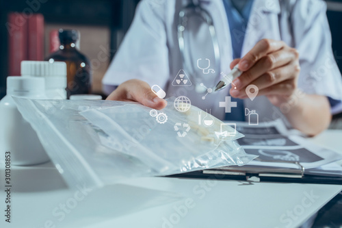 Female doctor at table with laptop and papers and showing pills in jar to a man patient sitting near. Medical technology networking concept.