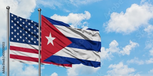 Foto United States and Cuba flag waving in the wind against white cloudy blue sky together