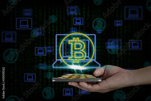 Human hand holding mobile smart phone with piles of coins and bitcoin symbol on binary background