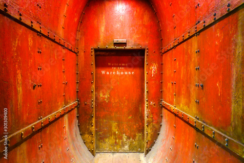 Canvas Print Welcome to the Warehouse text on grungy big red steel door entrance to Game Arca