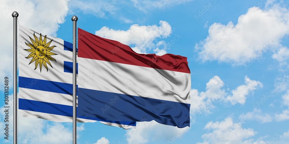 Uruguay and Netherlands flag waving in the wind against white cloudy blue sky together. Diplomacy concept, international relations.