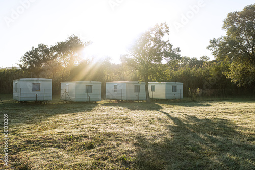 Some bungalows in a row in a green landscape camping with sun shining morning © jordieasy