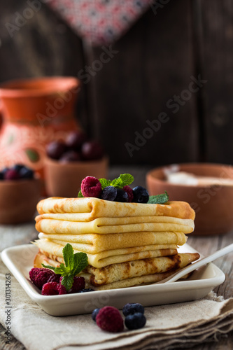 chocolate or maple syrup pouring over crepes. Closeup view of stack of thin pancakes, blini or crepes with honey photo