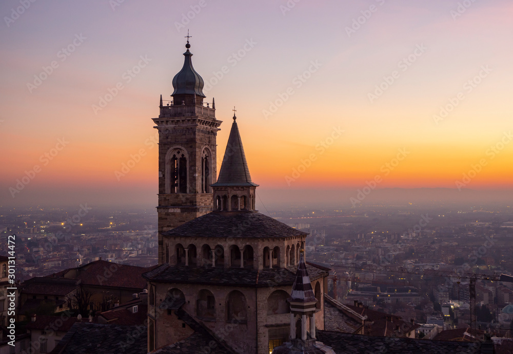 Bergamo, Italy. The old town. Amazing aerial view of the Basilica of Santa Maria Maggiore during the sunset. In the background the Po plain. Warm colors